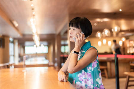 mature Asian woman talk on cellphone at a coffee shopの写真素材