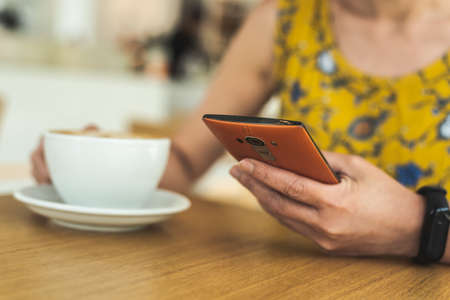 woman using cellphone at a coffee shop in the daytimeの写真素材