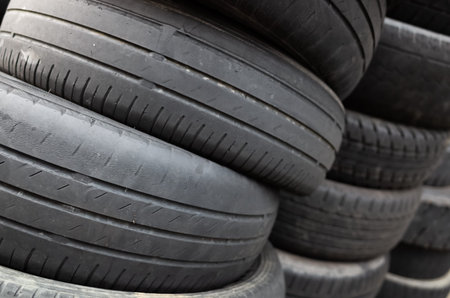 old used car tires stacked in piles in the daytimeの写真素材