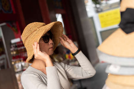 traveling woman shopping and picking a hat at the storeの写真素材