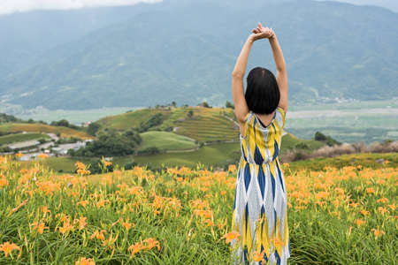asian woman feel free and stand in the yellow tiger lily farmの写真素材