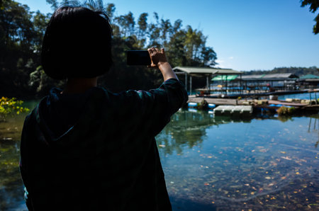 silhouette of Asian woman take a picture and stand near the famous Sun Moon Lake, Taiwanの写真素材