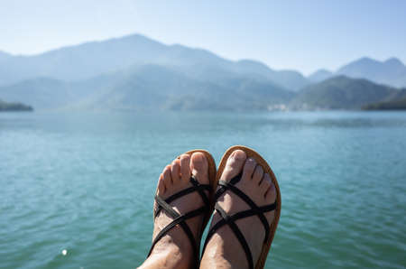 view of foot by woman relaxes by the lake sitting on the ground at famous Sun Moon Lake, Taiwanの写真素材
