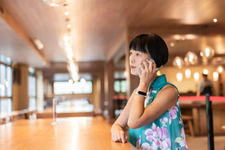 mature Asian woman talk on cellphone at a coffee shopの写真素材