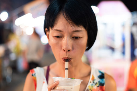 Asian woman holding the famous taiwanese bubble milk tea at night marketplace