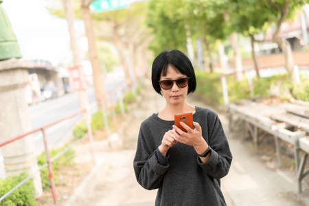 Asian woman using cellphone at the streetの写真素材