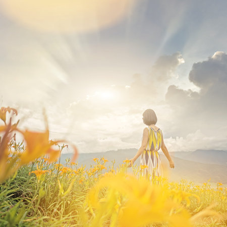asian woman feel free and stand in the yellow tiger lily farm