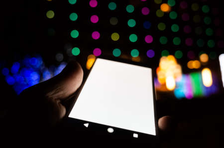 woman hold a cellphone with blank white screen at nightの写真素材