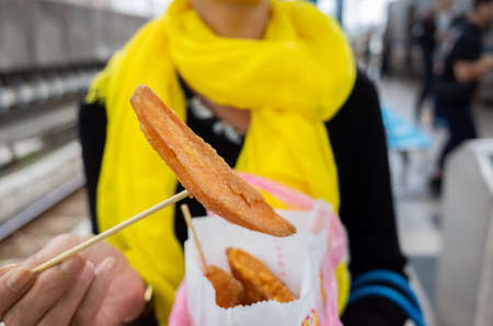 Asian woman eat taiwanese sweet potato fries in a cityの写真素材