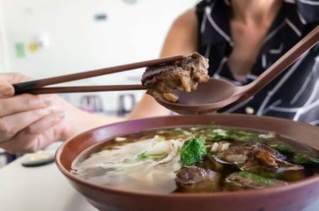 eating clear stewed beef noodle soup at Taiwanの写真素材
