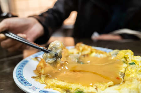 woman eat traditional Taiwanese snack of oyster omeletの写真素材