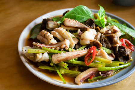 sauteed squid with vegetables in a dish on the tableの写真素材
