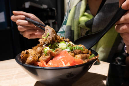 Japanese donburi with hot sliced pork and rice in the bowl on a tableの写真素材