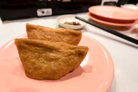 inarizushi on a dish at a fast sushi restaurantの写真素材