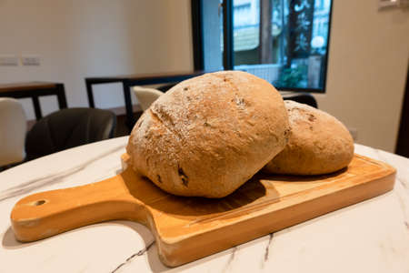 homemade round bread in a wooden plate on the tableの写真素材