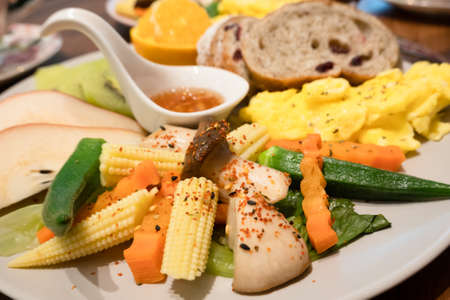 breakfast of bread, vegetables and fruits on a dish in the morningの写真素材
