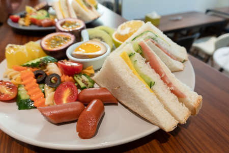 breakfast of bread, vegetables and fruits on a dish in the morningの写真素材