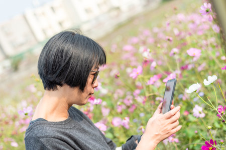 Asian woman take a picture on a flower in the outdoorの写真素材