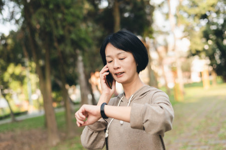 Asian woman talk on cellphone and using smart watchの写真素材