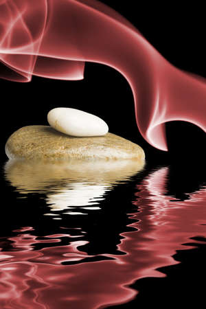 Zen stones surrounded by red smoke and reflected in the water の写真素材