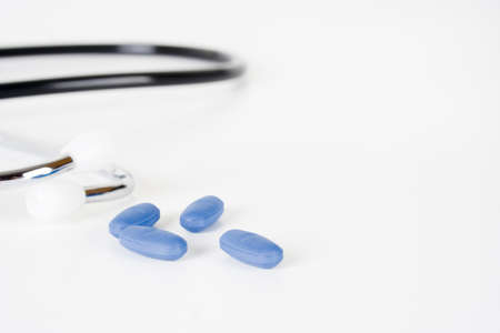 Blue pills and stethoscope on white background の写真素材