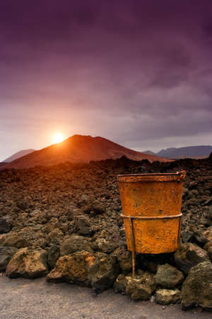 Sunset in Timanfaya with rusty metal basket in the foregroundの写真素材