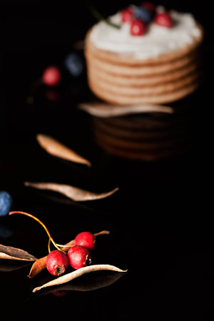 Cookies with cream cheese and blueberries on top surrounded with berries and dry leaves