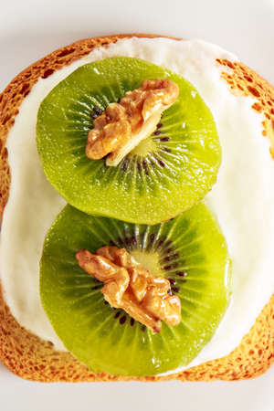 Toast with kiwi, cheese and walnuts on a white dish.View from aboveの写真素材