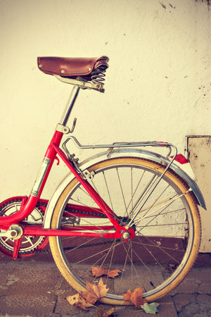 Retro bicycle with autumn leaves on the rear wheel. Vintage style. Vertical image