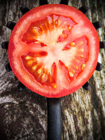 Half tomato on a toothed kitchen spoon on a old wooden table. Vertical image.の写真素材