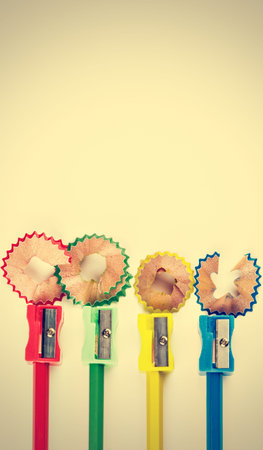 Colored pencils, sharpener and shavings on vintage style. Vertical image.