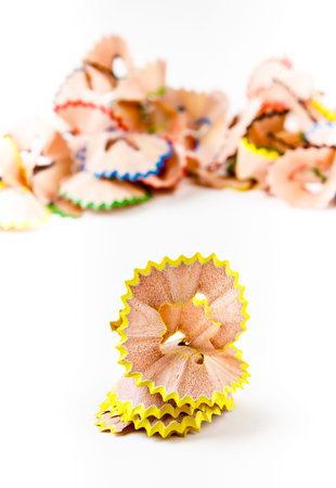 Yellow pencil shavings with more shavings at the background. Vertical image.