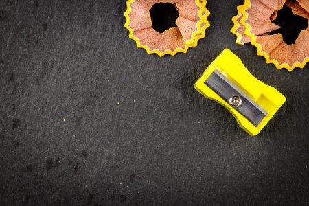 Yellow shavings pencil and yellow pencil sharpener on black background. Horizontal image.