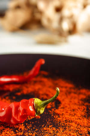 Closeup red pepper with ground paprika on brown dish over white wood. Vertical image.の写真素材