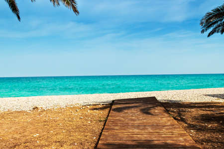 Wooden walkway on the beach with palm trees. Horizontal image.の写真素材