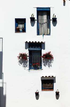 Windows decorated with flowers on the wall of a white facade. Vertical image.の写真素材