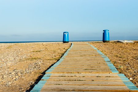 Wooden walkway on the beach with two litter bins in the background. Horizontal imageの写真素材