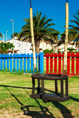 Swing in the playground with colored fences in the background. Vertical image.の写真素材