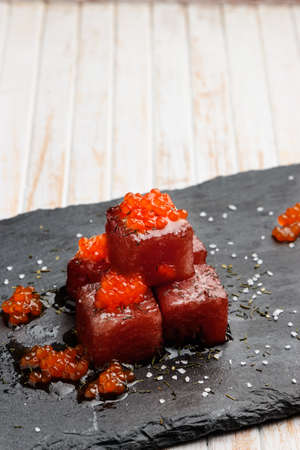 Tuna sashimi dipped in soy sauce with salmon roe, thick salt and dill on slate stone. Raw fish in traditional Japanese style. Vertical image.の写真素材