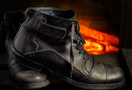 Casual gray leather shoes for men on wooden board with fireplace in the background. Dark mood style. Horizontal image.の写真素材