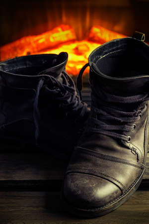 Casual gray leather shoes for men on wooden board with fireplace in the background. Dark mood style. Vertical image.の写真素材