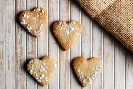 Delicious home-made heart-shaped cookies sprinkled with icing sugar in a wooden board. Horizontal image seen from above. の写真素材