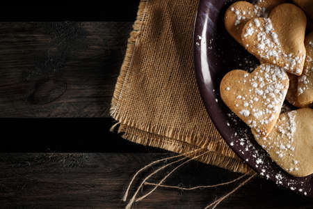Delicious home-made heart-shaped cookies sprinkled with icing sugar on sackcloth and wooden boards. Horizontal image seen from above.の写真素材