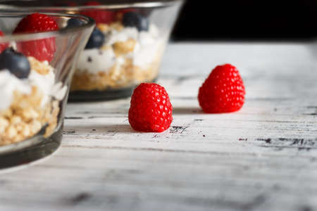 Raspberries, blueberries, cereals and yogurt in a glass bowl on wooden slats. Healthy breakfast for a healthy life. Horizontal image.の写真素材