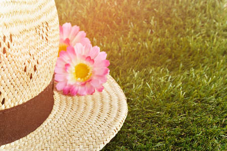 Straw hat with flower on the brim on the grass.の写真素材