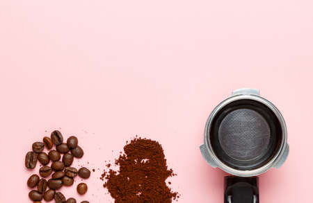 Detail of espresso machine filter holder, ground coffee and coffee beans on pink background. Space for text.の写真素材