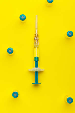 Syringe with several medical vials for injecting on yellow background. Top view.の写真素材