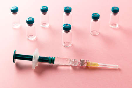 Syringe with several medical vials for injecting on pink background.の写真素材