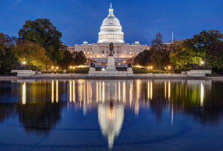 The famous illuminated United States Capitol in Washington DC at night reflected in a pondの写真素材