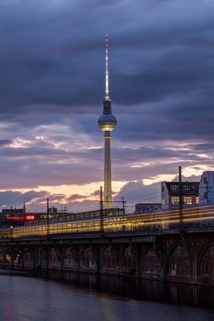 The famous Television Tower and the river Spree with a motion blurred commuter train in Berlin at twilightの写真素材
